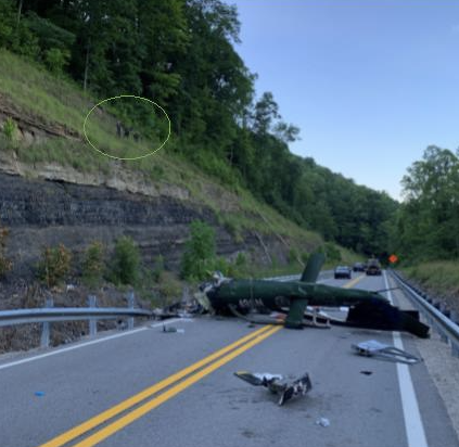 Helicopter resting on it's right side on an asohalt road