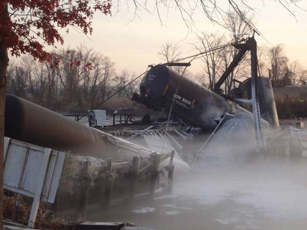 Photo of the breached tank car leaning off the bridge and the vinyl chloride vapor cloud.