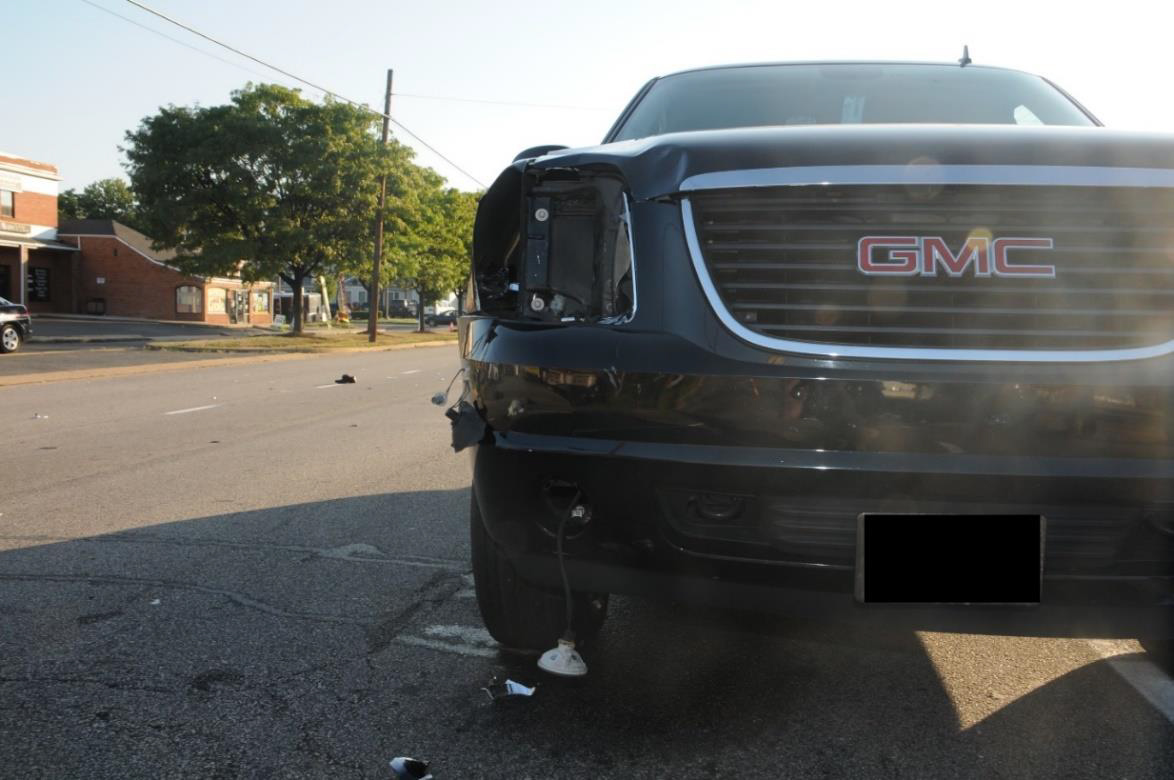 Photograph of crash SUV showing damage on right side to headlight, hood, and fender.